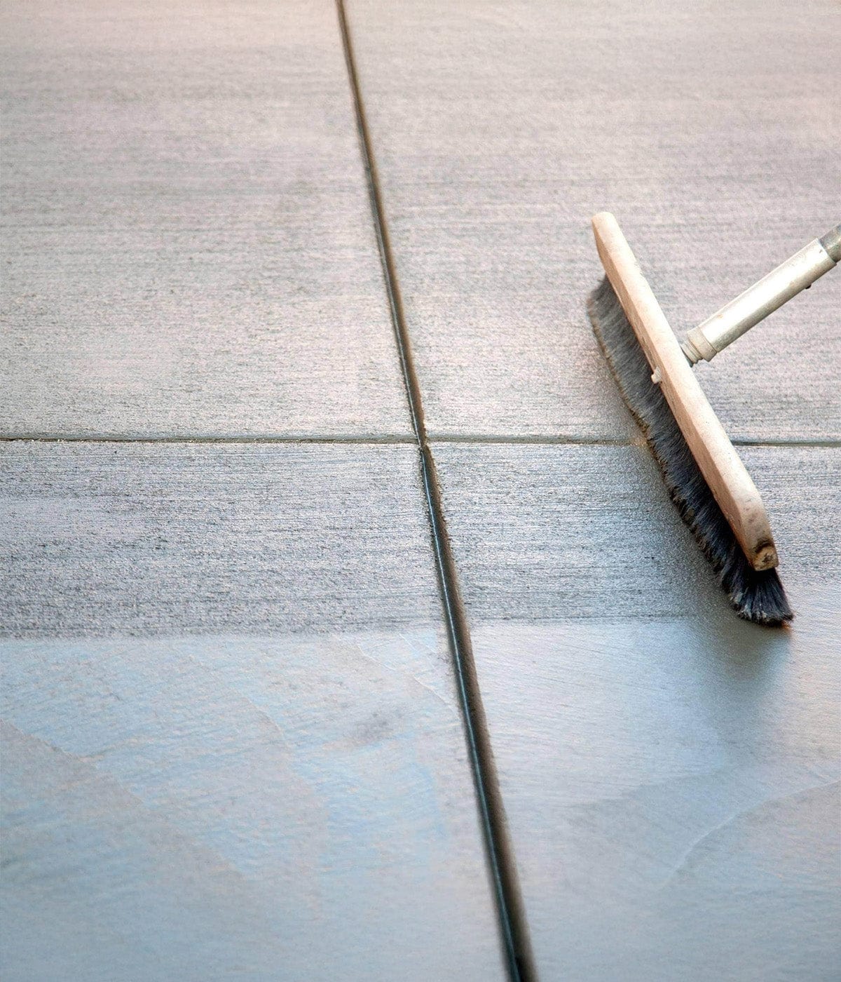 Brush adding texture to freshly poured concrete, showcasing custom concrete work - AllDone Construction.